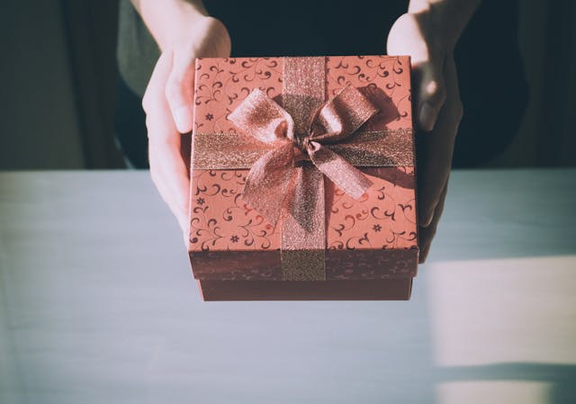 Imagen de un regalo en unas manos que se disponen a entregarlo